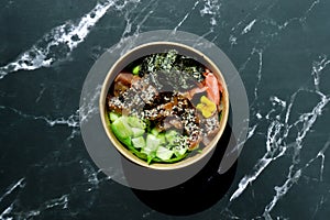 Top view of wok box, bowl of rice on black background. Rice fried and stirred with salmon, avocado, onion, mushrooms, broccoli