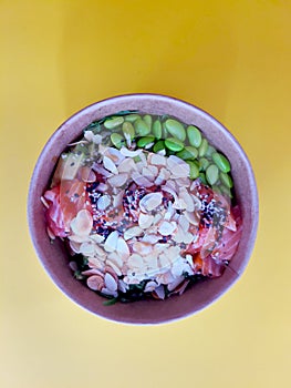 Top view of wok box, bowl of rice on black background. Rice fried and stirred with salmon, avocado, onion, mushrooms, broccoli