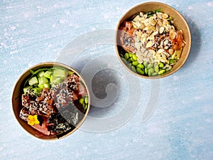 Top view of wok box, bowl of rice on black background. Rice fried and stirred with salmon, avocado, onion, mushrooms, broccoli