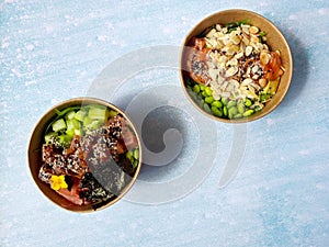 Top view of wok box, bowl of rice on black background. Rice fried and stirred with salmon, avocado, onion, mushrooms, broccoli