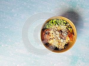 Top view of wok box, bowl of rice on black background. Rice fried and stirred with salmon, avocado, onion, mushrooms, broccoli