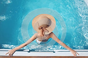 Top view of Woman in beach hat enjoying in swimming pool on luxury tropical resort. Exotic Paradise. Travel, Tourism and Vacation