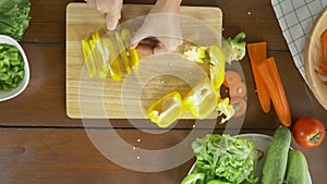 Top view of woman chief making salad healthy food and chopping bell pepper on cutting board in the kitchen