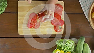 Top view of woman chief making salad healthy food and chopping tomato on cutting board in the kitchen