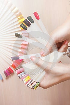 Top view woman choose manicure colorful nail polish. Nail technician shows the color palette of nail services in beauty salon stor