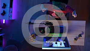 Top view of woman at the computer, won the mission in the game, pumping her fists winning gesture.