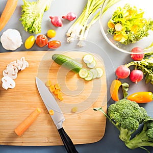Top view of woman cooking healthy food: cutting vegetable ingredients