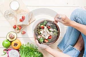 Top view woman eating chicken salad with fruits, vegetables, who