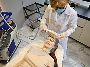 Top view of a woman getting facial laser treatment for hair removal, skin smoothing and age and pigments spots treatment on her