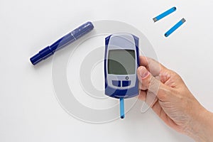 Top view of woman hand holding glucose meter with blooded test strip with empty screen to fill your datas on white background