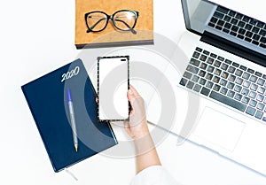 Top view of woman hand using smartphone at the white office desk