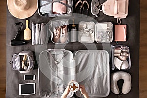 Top view woman hands getting ready to travel vacation packing suitcase use konmari method