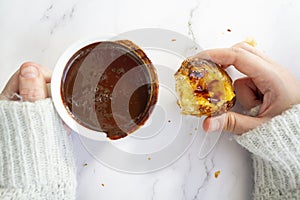 Top view of woman hands holding cup with hot chocolate and portuguese custard tart called pastel de nata photo
