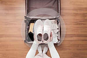 Top view of woman hands packing a boots in a luggage suitcase for a new journey.