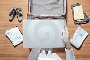 Top view of woman hands packing laptop in luggage suitcase for a new journey.