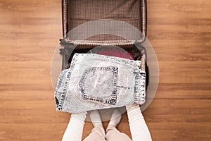 Top view of woman hands packing a luggage for a new journey.