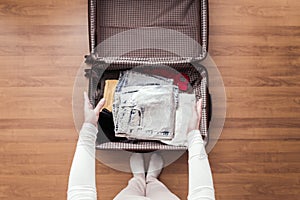 Top view of woman hands packing a luggage for a new journey.