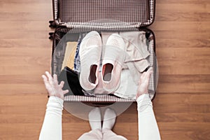 Top view of woman hands packing a luggage for a new journey.