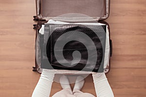 Top view of woman hands packing office clothes in a luggage suitcase for a new journey.