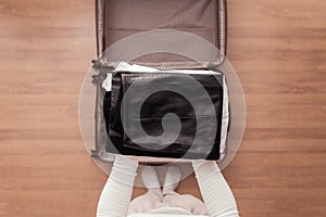 Top view of woman hands packing office clothes in a luggage suitcase for a new journey.