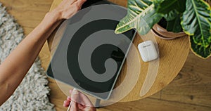 Top view. Woman hands plugging the charging cable in the port of a tablet device to charge the battery.