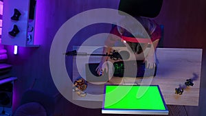 Top view of woman in headphones with microphone playing game on PC with Chroma key green screen, lost round, advertising