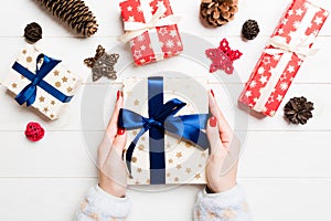 Top view of a woman holding a gift box in her hands on festive wooden background. Christmas decorations. New year time concept