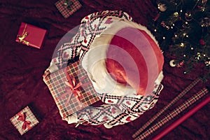 Top view of woman in red santa claus hat holding wrapping christmas gifts boxe for family standing on fluffy plaid near christmas.