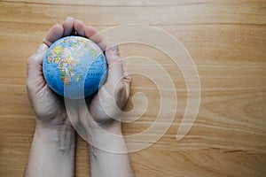 Top view of woman`s hand with globe on wooden table. Empty space