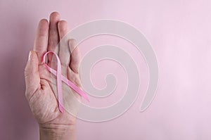 Top view of woman`s hand and pink ribbon on it.Concept of healthcare and breast cancer photo