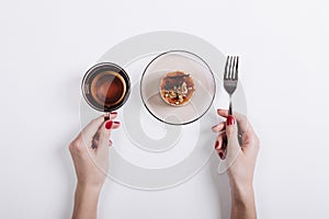 Top view of a woman's hands holding a cup of tea and fork, on th