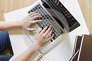 Top view of woman's hands working with laptop.