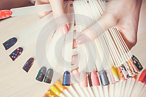Top view woman selects yellow color shellac nail polish.Nail technician shows the color palette of nail services in