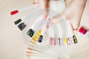 Top view woman selects yellow color shellac nail polish.Nail technician shows the color palette of nail services in