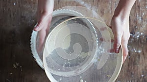 Top view of woman sieving flour in plate