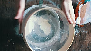 Top view of woman sieving flour in plate