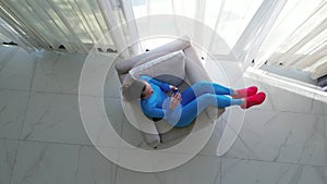 Top view. Woman sitting comfortably in a chair near a large window in a luxurious villa.