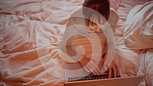 Top view of woman skilled freelancer using portable laptop computer for distance work, while relaxing in bed.