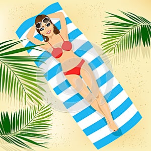 Top view of woman with sunglasses in bikini lying on colorful beach towel