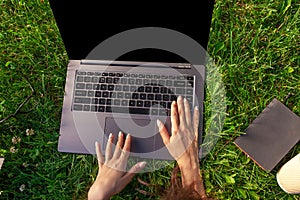 Top view. Woman working on laptop pc computer with blank black empty screen to copy space in park on green grass