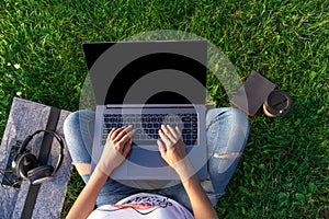 Top view. Woman working on laptop pc computer with blank black empty screen to copy space in park on green grass