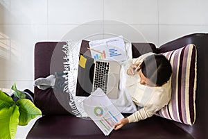 Top view woman working on laptop with talking smart phone on the sofa in the house