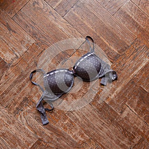 Woman bra thrown on wooden floor