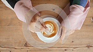 top view of women hand stirring coffee with spoon.