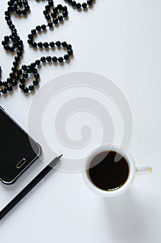 Top view of women`s business work desk. Flat lay fashion feminine workspace with phone, cup of coffee, pen and jewelry