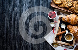 Top view of a wood table full of cakes, fruits, coffee, biscuits