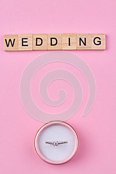 Top view of wooden blocks with word WEDDING and engagement ring in box.