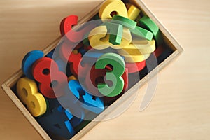 Top view of wooden box filled with colorful numbers, used for children learning