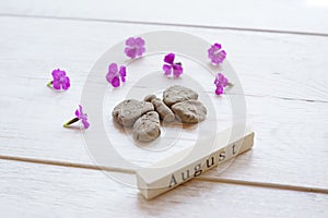 Top view of wooden calendar with August sign, clay butterfly and pink flowers