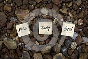 Top view of wooden cube written with Mind Body Soul on a brown rock background